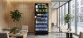 Vending machine in a modern office setting with chairs and plants.